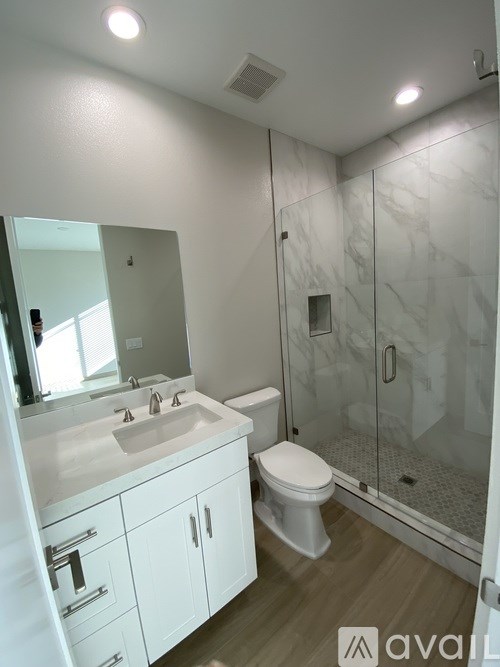 A bathroom with a white sink, toilet, and a walk-in shower.