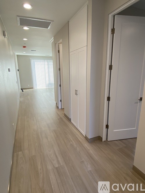 A long hallway with white doors and a wooden floor.