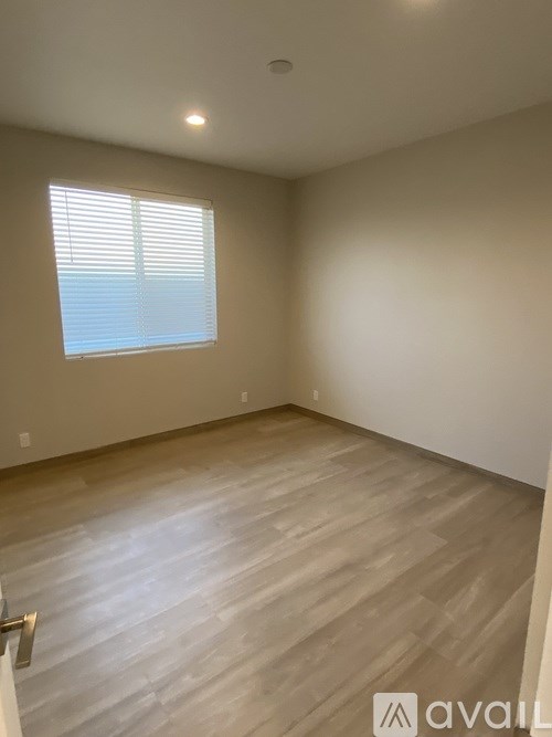 A room with wooden flooring and a window with blinds.