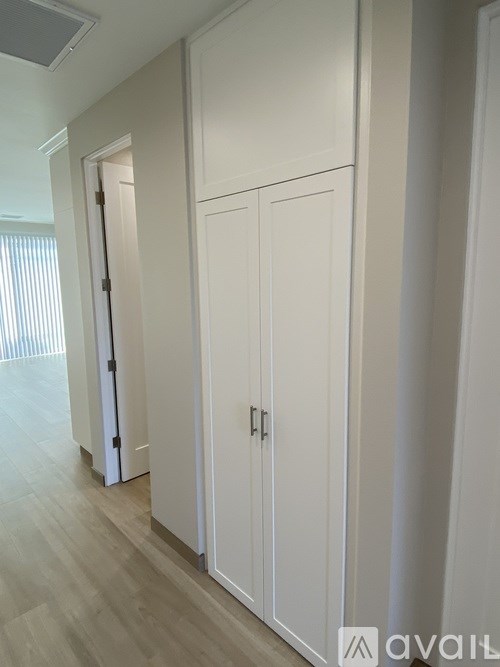 A white cabinet with a door is in the middle of a room.