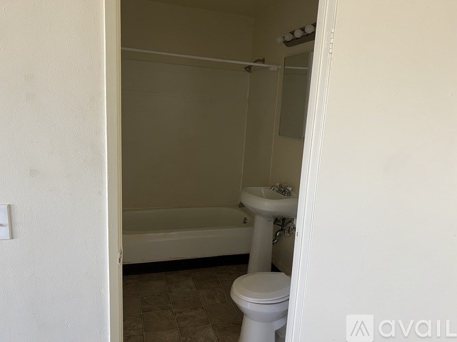 A white toilet sits in a bathroom next to a bathtub.