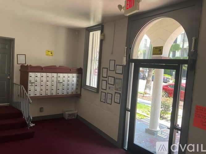 A hallway with a red carpet, a staircase, and a bulletin board with papers on it.