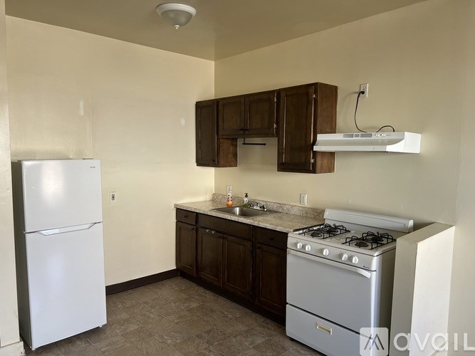 A kitchen with a white refrigerator, a white stove, and brown cabinets.