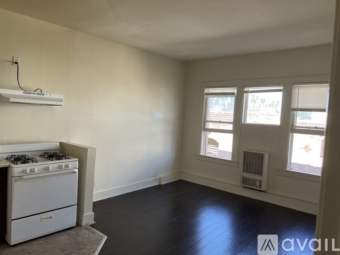 A white stove is in a room with a white wall and a window.