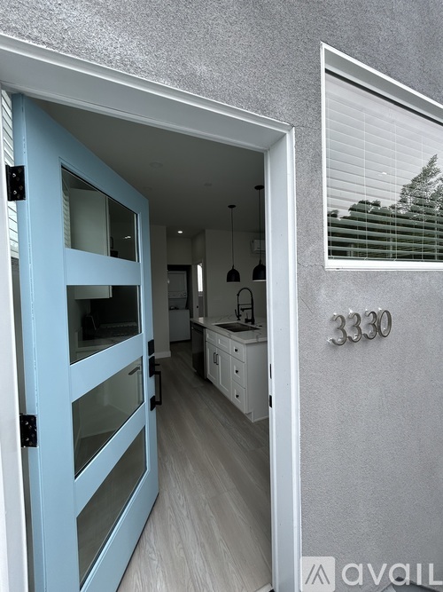 A blue door opens to a kitchen with white cabinets.
