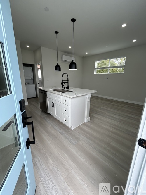 A modern kitchen with a white countertop and light wood flooring.
