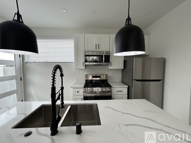 A modern kitchen with a marble countertop and stainless steel appliances.