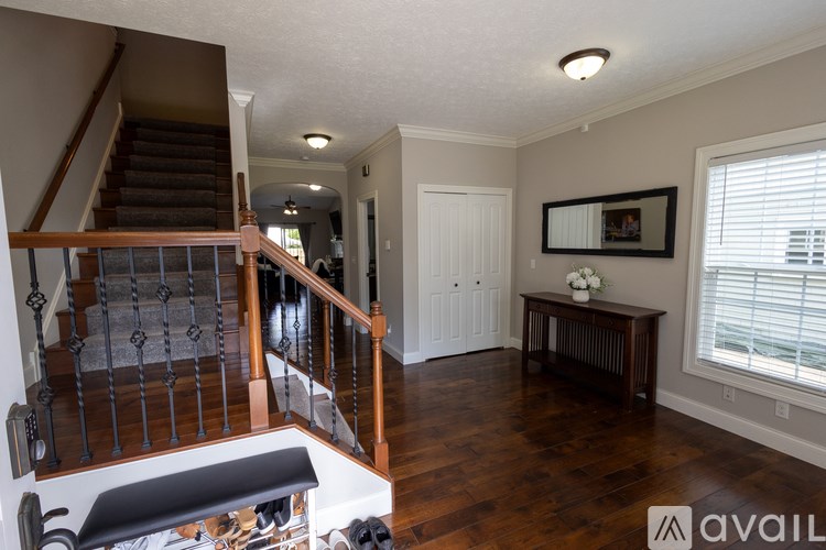 A living room with a staircase and a wooden floor.