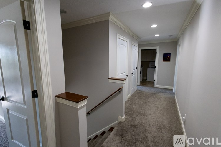 A hallway with a carpeted floor and white walls.