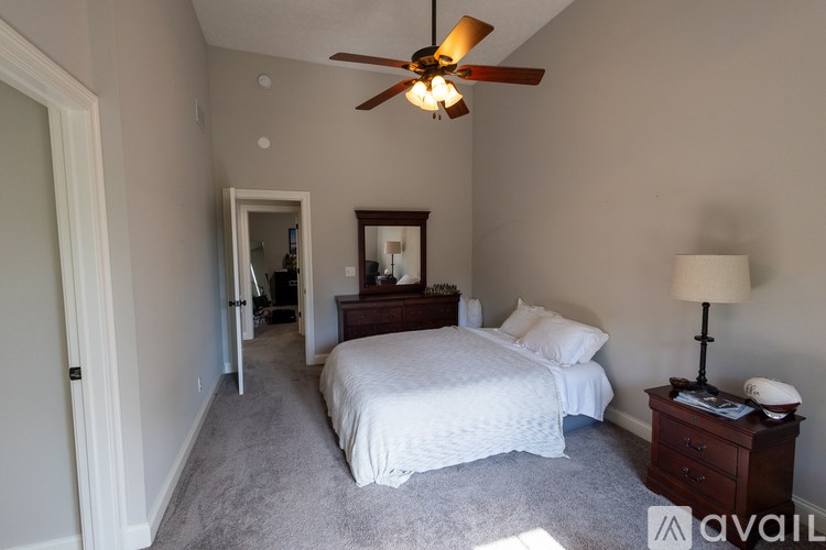 A bedroom with a bed, dresser, mirror, and ceiling fan.