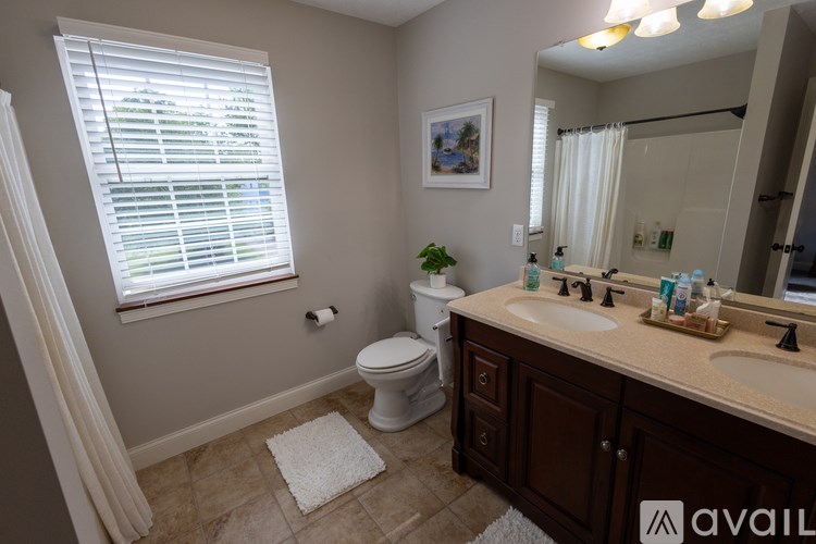 A bathroom with a toilet, sink, and window.