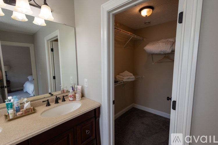 A bathroom with a sink, mirror, and a towel on a shelf.