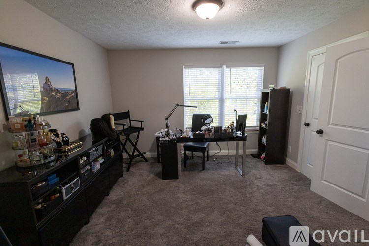A room with a black couch, a chair, a desk, and a computer setup.