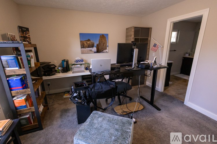 A room with a computer desk, a chair, and a bookshelf.