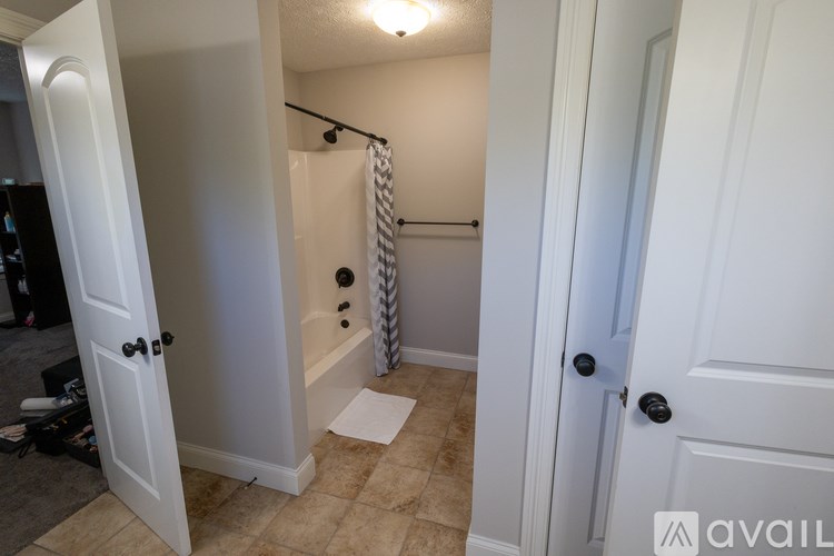 A bathroom with a white door and a white shower curtain.