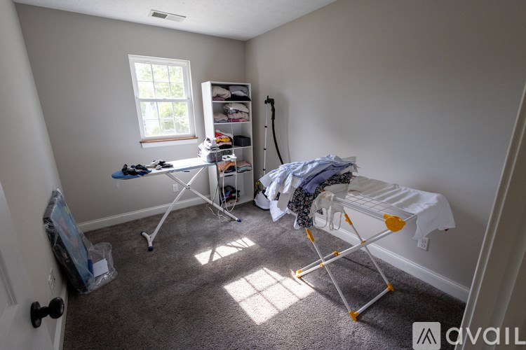 A room with a ironing board and ironing clothes.