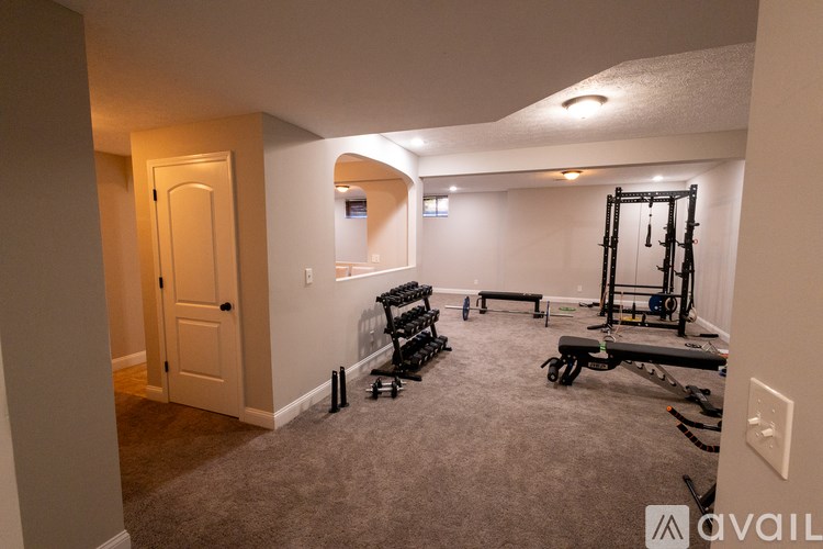 A gym with a squat rack, bench, and weights.