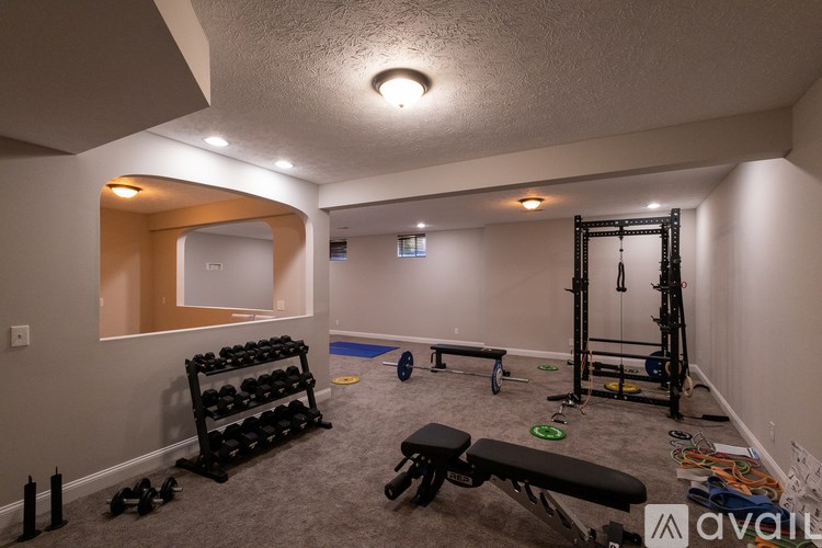 A room with a mirror, a bench, and a rack of dumbbells.