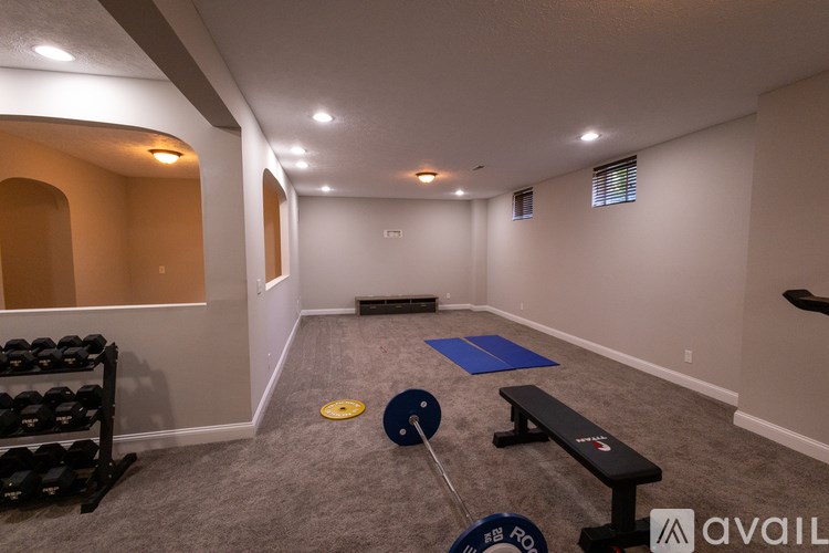 A gym with a bench, weights, and a yoga mat.