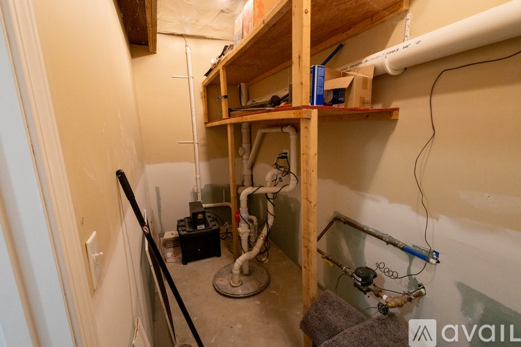 A room with a lot of pipes and a wooden shelf.