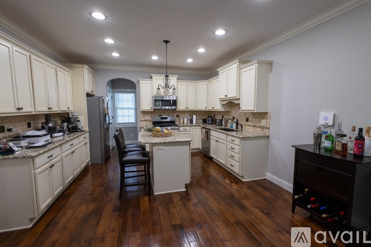 A kitchen with white cabinets and a wooden floor.