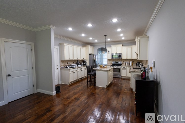 A kitchen with white cabinets and a wooden floor.