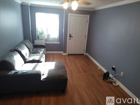 A living room with a black couch and a wooden floor.