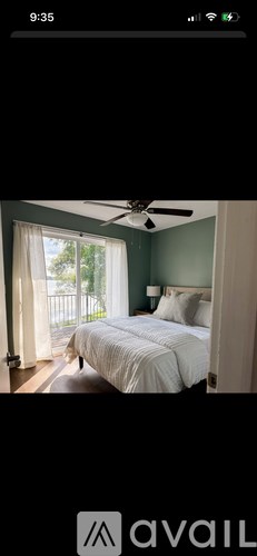 A bedroom with a bed, a ceiling fan, and a window with curtains.