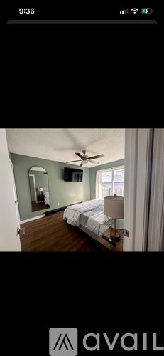 A bedroom with a bed, a ceiling fan, and a mirror.