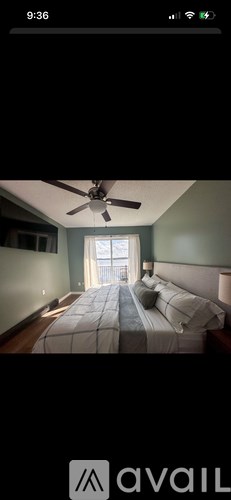 A bedroom with a bed, a ceiling fan, and a window.
