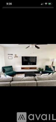 A living room with a couch, a television, and a ceiling fan.