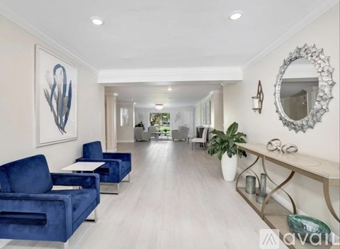 A living room with blue chairs and a white wall.