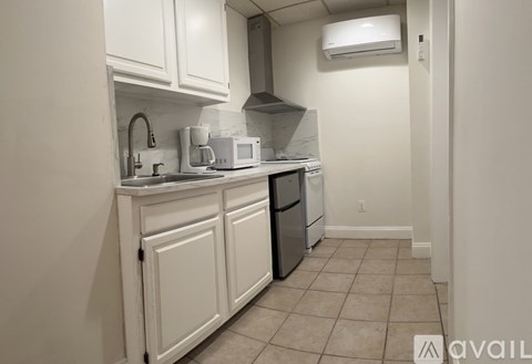 A kitchen with white cabinets and a black fridge.