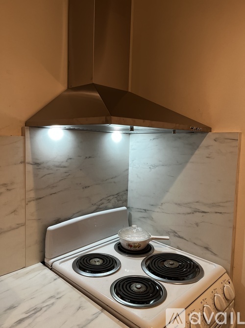 A white stove with four burners is on a marble countertop.