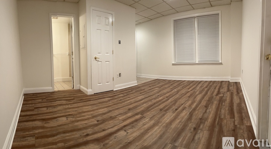 A room with wooden flooring and a window with blinds.
