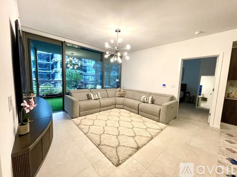 A living room with a grey sofa and a chandelier.