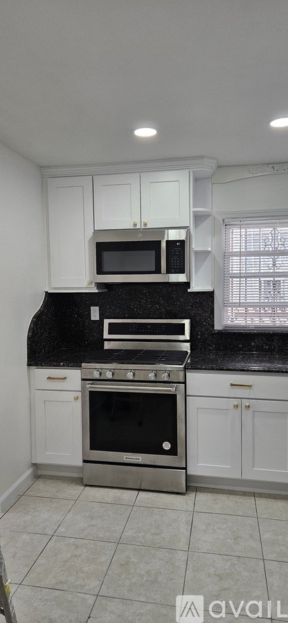 A kitchen with white cabinets and a black countertop.