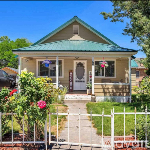 A small house with a green roof and a white picket fence.