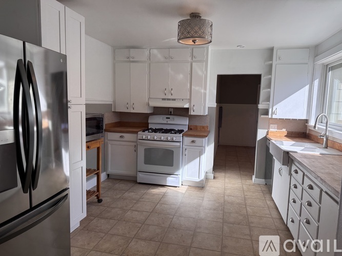 A kitchen with a stainless steel refrigerator and white cabinets.