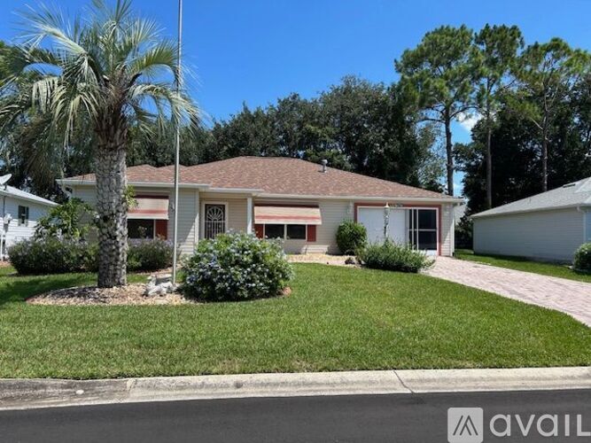 A house with a red roof and a palm tree in front.