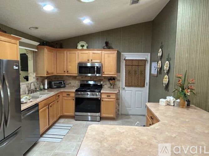 A kitchen with wooden cabinets and a stainless steel refrigerator.