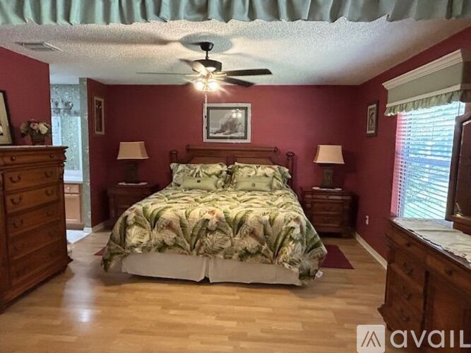 A bedroom with a bed, dresser, and ceiling fan.