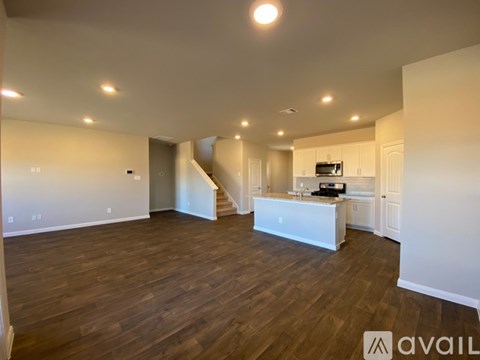 A spacious living room with wooden flooring and a staircase leading to the upper level.