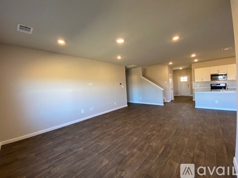 A spacious room with wooden flooring and a staircase leading to another room.