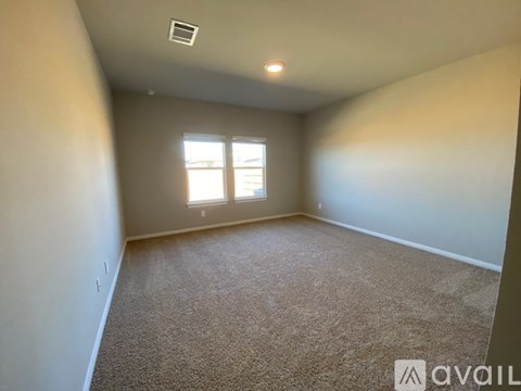 A room with carpeted floor and a window letting in natural light.