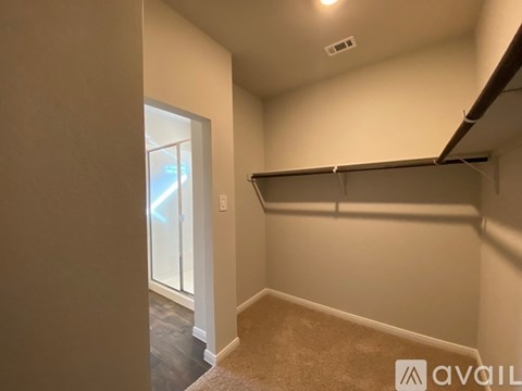 A room with a carpeted floor, a white door, and a black pipe on the ceiling.