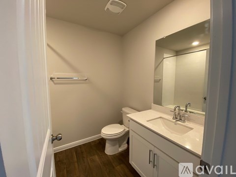 A small bathroom with a toilet, sink, and mirror.
