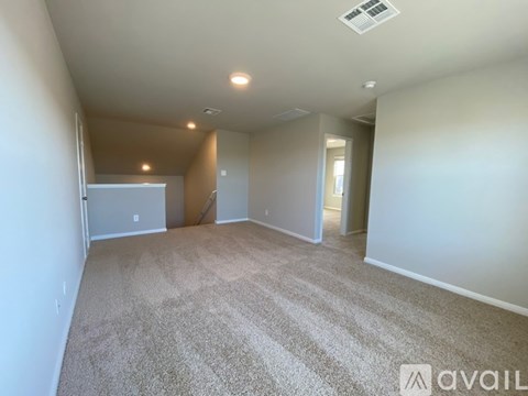 A spacious room with carpeted floor and a ceiling fan.