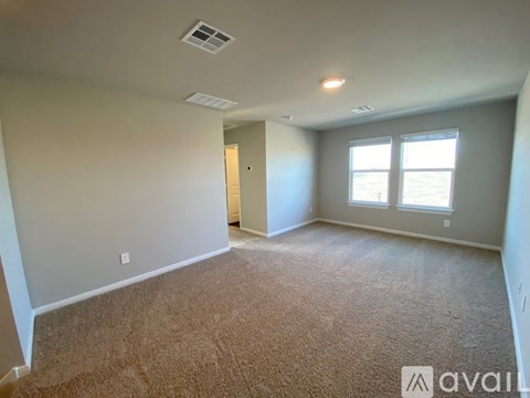 A room with carpeted floor, a door, and two windows.