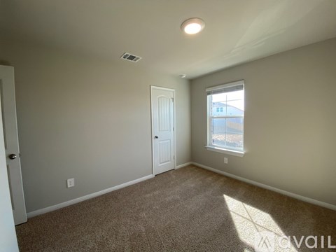 A room with a carpeted floor, a door, and a window.